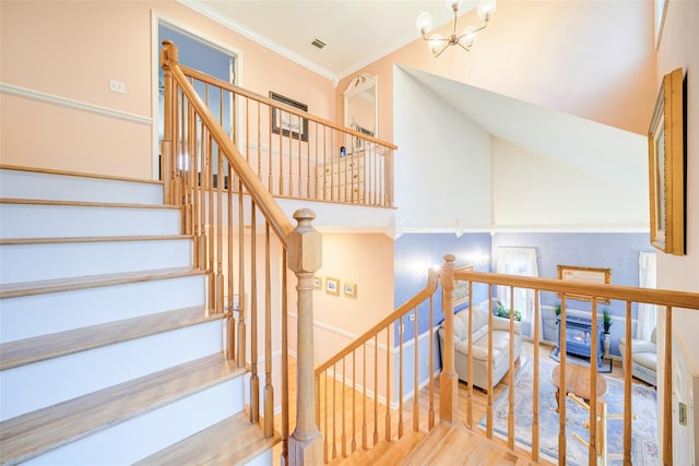 stairs with crown molding, wood finished floors, a chandelier, a high ceiling, and visible vents