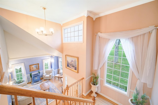 interior space with wood finished floors, a chandelier, a high ceiling, baseboards, and ornamental molding