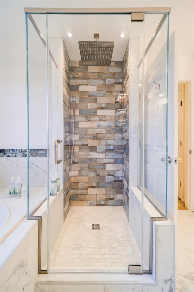bathroom featuring marble finish floor, a garden tub, and a stall shower