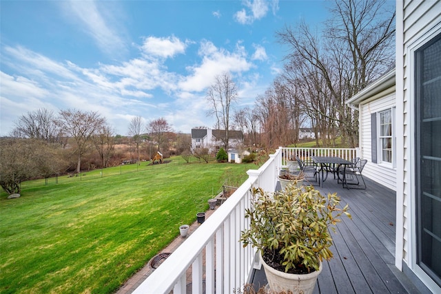 wooden terrace featuring a lawn and outdoor dining space