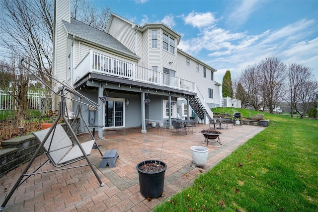 back of house with stairway, a yard, a wooden deck, a patio, and a fire pit