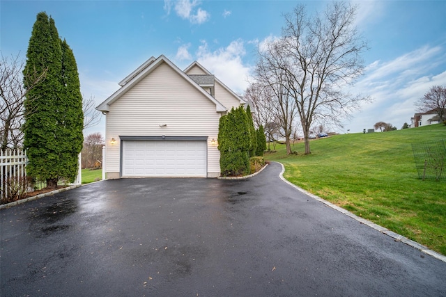 view of property exterior featuring a lawn, driveway, and fence