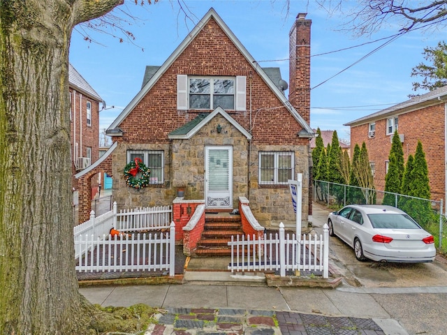 view of front facade featuring a chimney, a fenced front yard, and stone siding