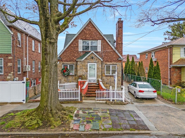 view of front of home with a chimney, cooling unit, driveway, and a fenced front yard