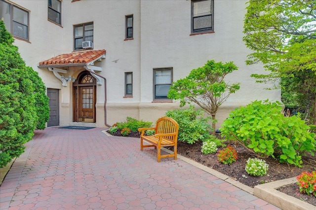 entrance to property with a patio, stucco siding, a tile roof, and cooling unit