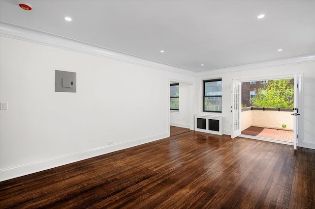 empty room featuring baseboards, ornamental molding, wood finished floors, and a healthy amount of sunlight