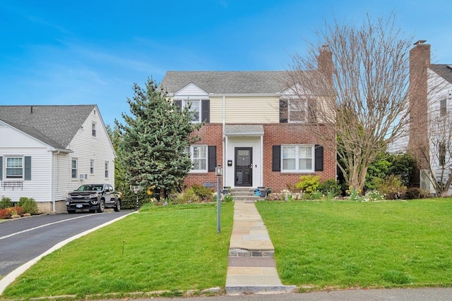 view of front of property with a front yard, aphalt driveway, and brick siding