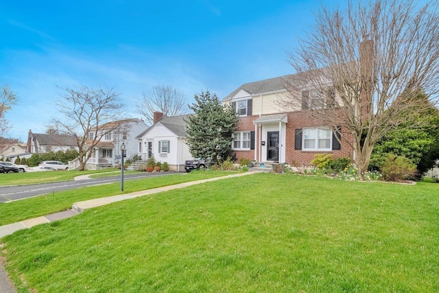 view of front of property featuring a residential view, a front yard, and brick siding