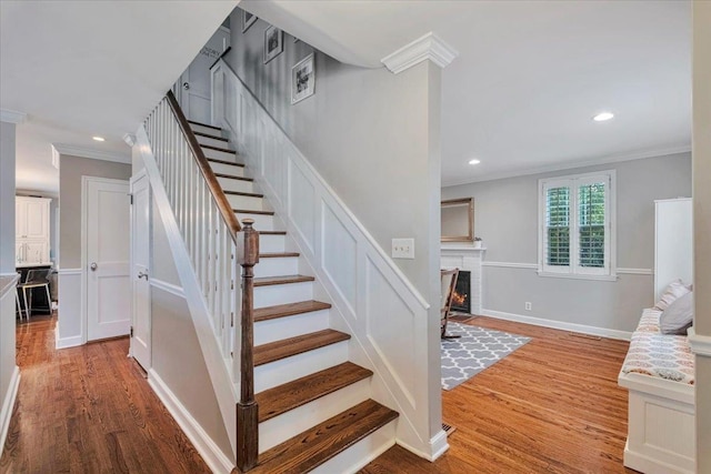 staircase featuring wood finished floors, crown molding, recessed lighting, and baseboards