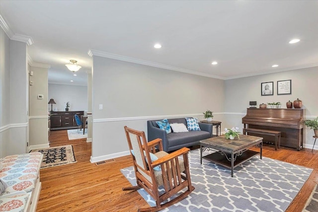 living room featuring ornamental molding, recessed lighting, baseboards, and light wood-type flooring