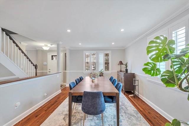 dining space featuring baseboards, ornate columns, wood finished floors, and stairs