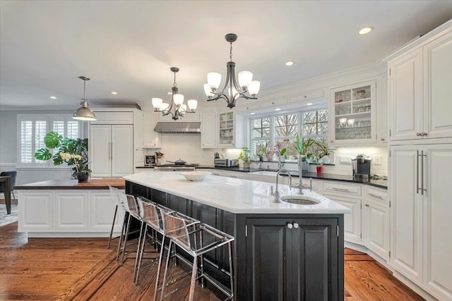 kitchen with an inviting chandelier, an island with sink, white cabinets, and a sink