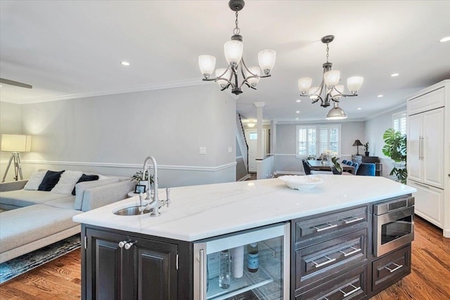 kitchen featuring beverage cooler, stainless steel microwave, a chandelier, open floor plan, and crown molding
