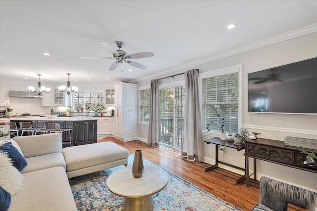 living room featuring crown molding, a wealth of natural light, and ceiling fan with notable chandelier