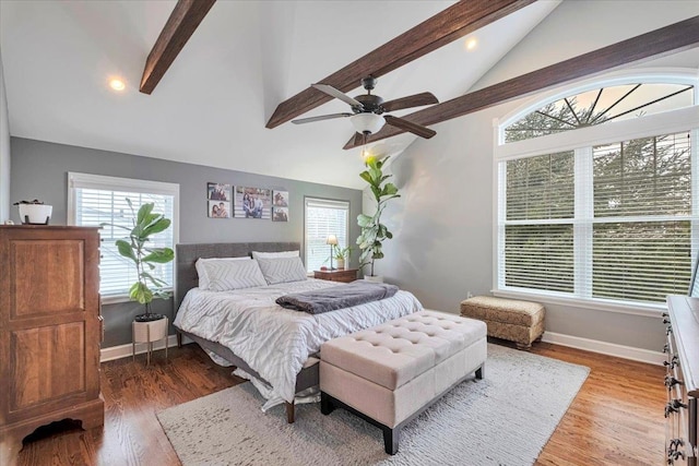 bedroom with beam ceiling, wood finished floors, and multiple windows