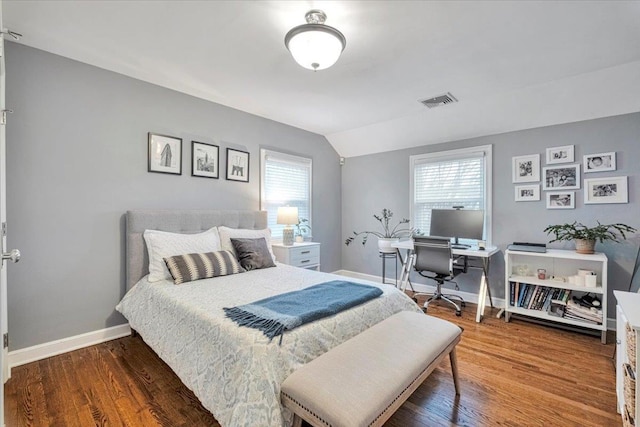 bedroom with lofted ceiling, wood finished floors, visible vents, and baseboards