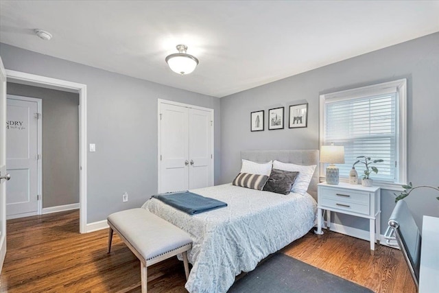 bedroom featuring baseboards, wood finished floors, and a closet