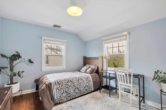 bedroom featuring baseboards, wood finished floors, multiple windows, and lofted ceiling