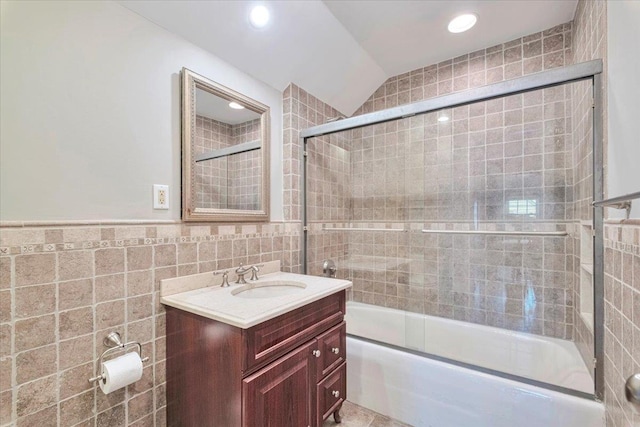 bathroom featuring recessed lighting, tile walls, vanity, combined bath / shower with glass door, and lofted ceiling