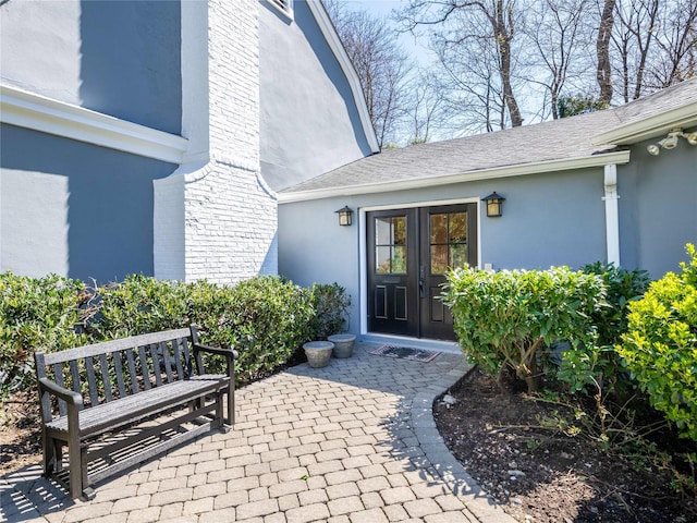 4 Terrace Ct, Port Washington, NY 11050 - property entrance with stucco siding, french doors, a shingled roof, and a patio area