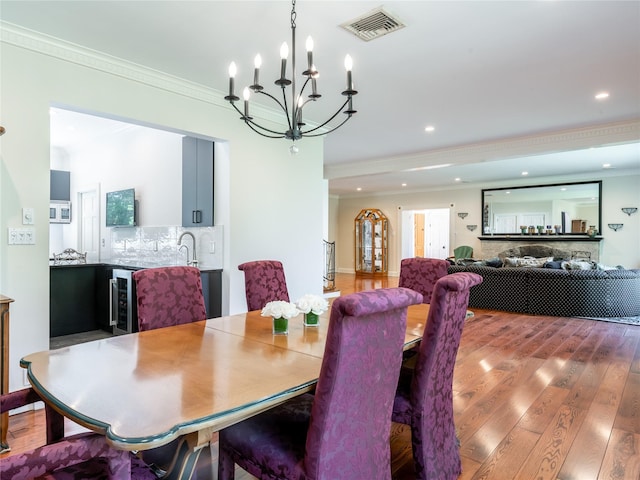 4 Terrace Ct, Port Washington, NY 11050 - dining area with ornamental molding, wine cooler, a chandelier, wood finished floors, and recessed lighting