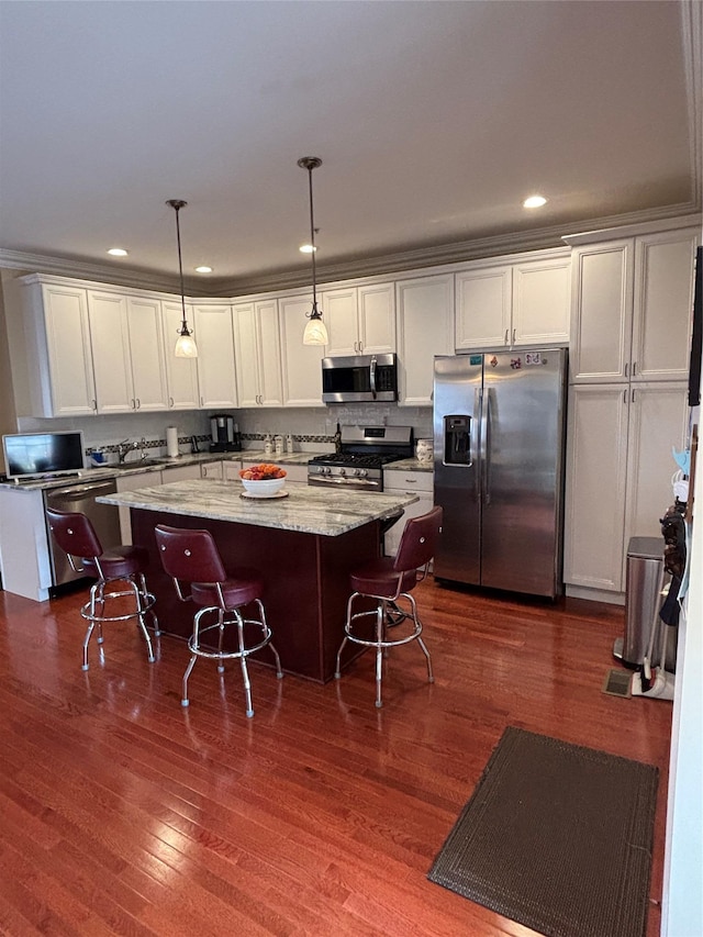 kitchen featuring light stone counters, a center island, dark wood-type flooring, decorative light fixtures, and appliances with stainless steel finishes