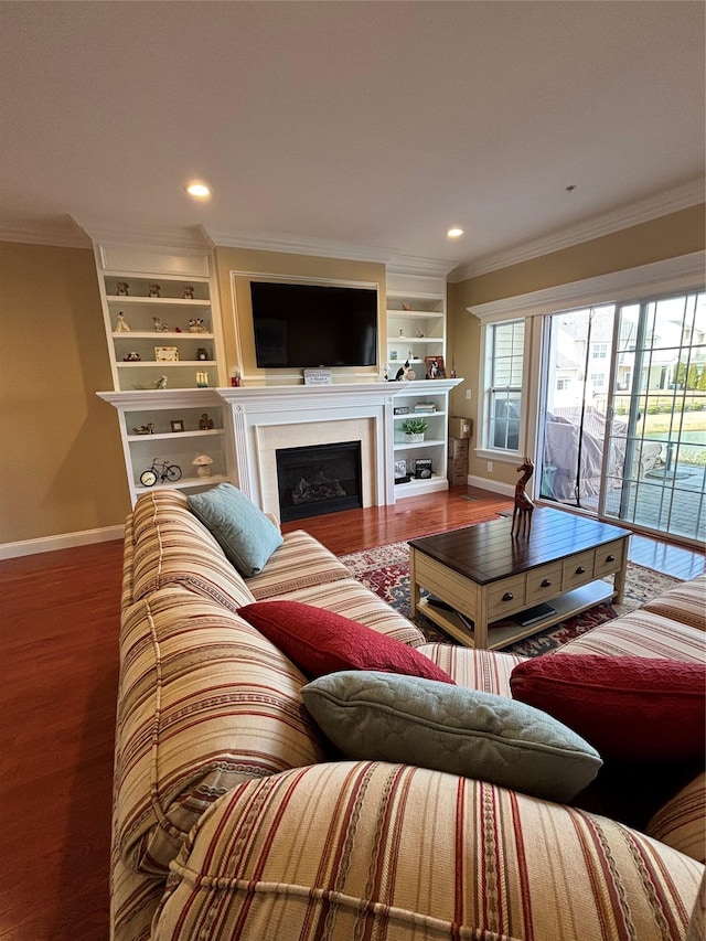 living area with wood finished floors, a fireplace, baseboards, and ornamental molding