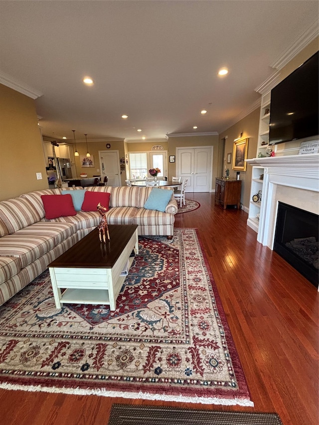 living area with wood finished floors, a fireplace, ornamental molding, and recessed lighting
