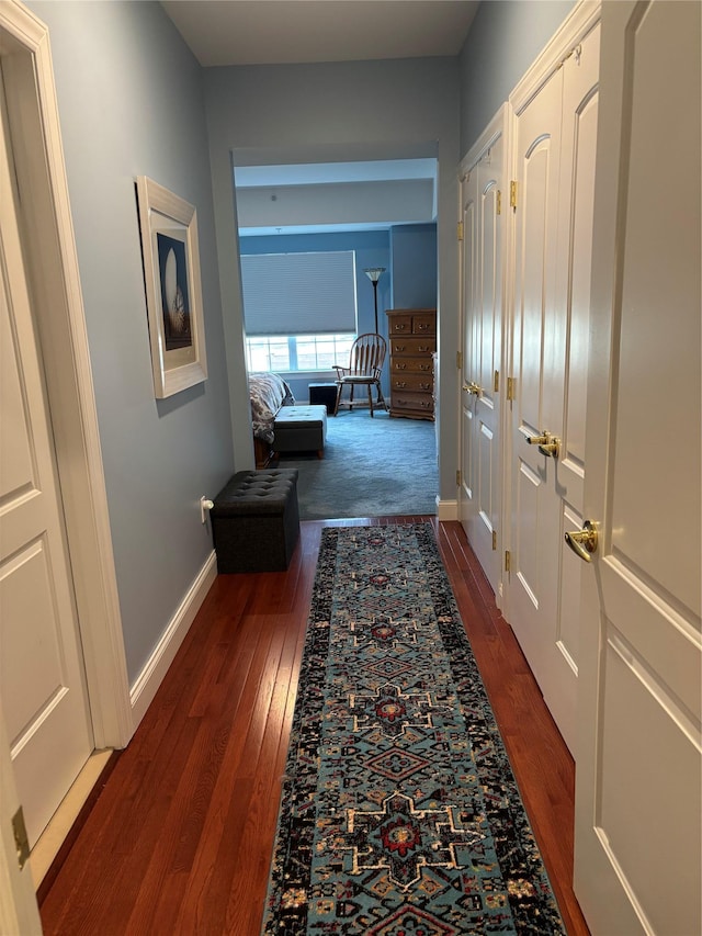 hallway with dark wood-style floors and baseboards