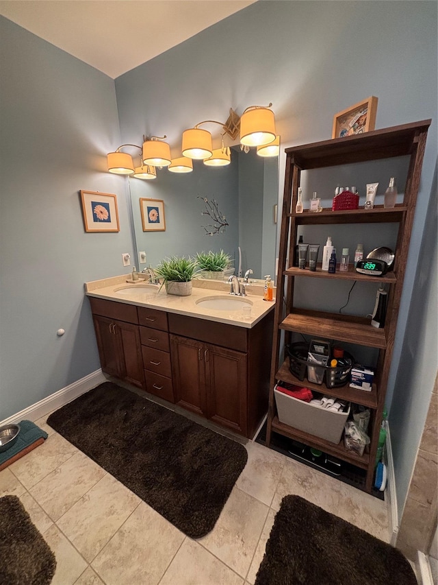 full bathroom with a sink, baseboards, double vanity, and tile patterned flooring