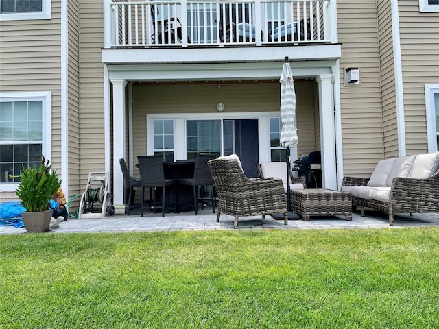 rear view of property featuring a yard, a patio area, and a balcony