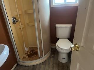 full bathroom with a shower stall, baseboards, toilet, and wood finished floors