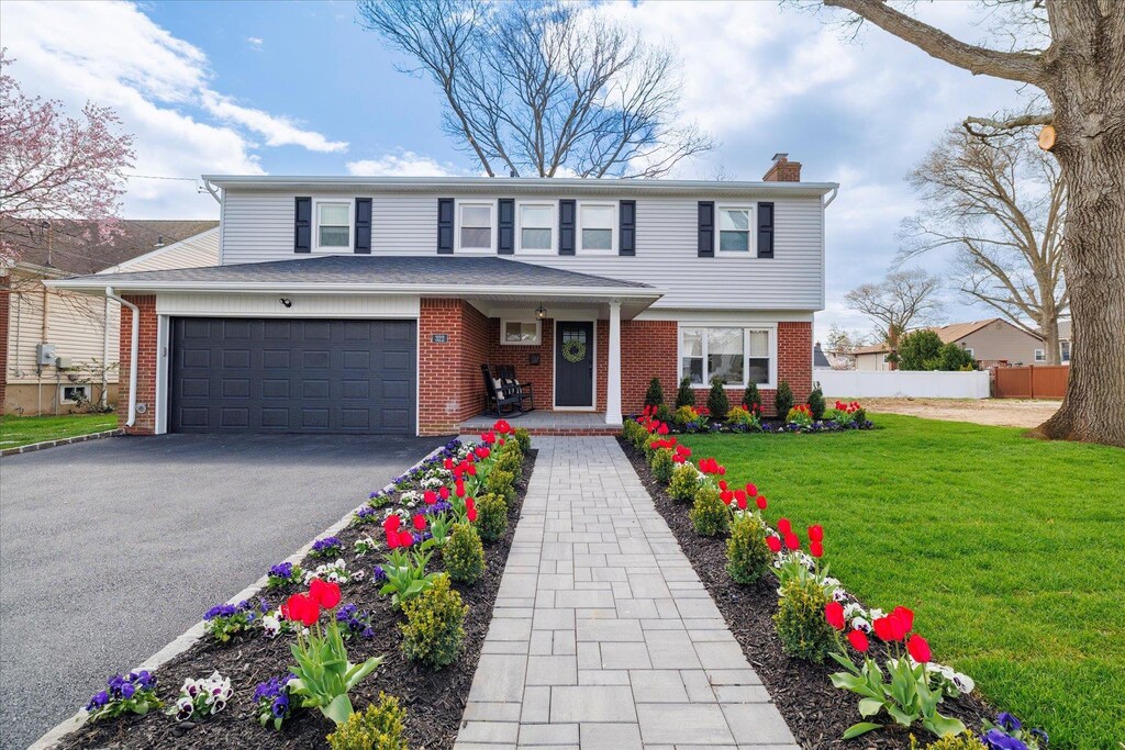 322 Dennis St, Oceanside, NY 11572 - traditional home with a chimney, fence, driveway, brick siding, and a garage