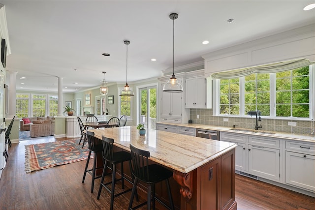 kitchen with a sink, dark wood-type flooring, open floor plan, a kitchen bar, and white cabinets