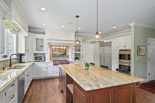 kitchen featuring stainless steel appliances, a sink, dark wood-style floors, a center island, and crown molding