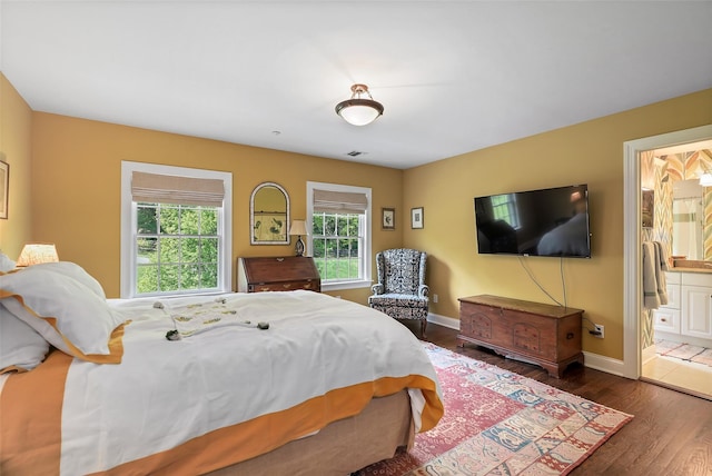 bedroom featuring wood finished floors, baseboards, and ensuite bathroom