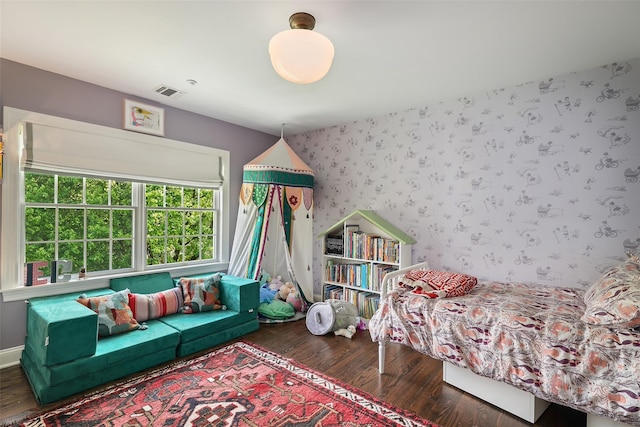 bedroom with wood finished floors and wallpapered walls