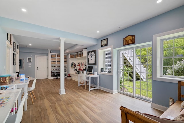 living area with decorative columns, baseboards, wood finished floors, recessed lighting, and stairs