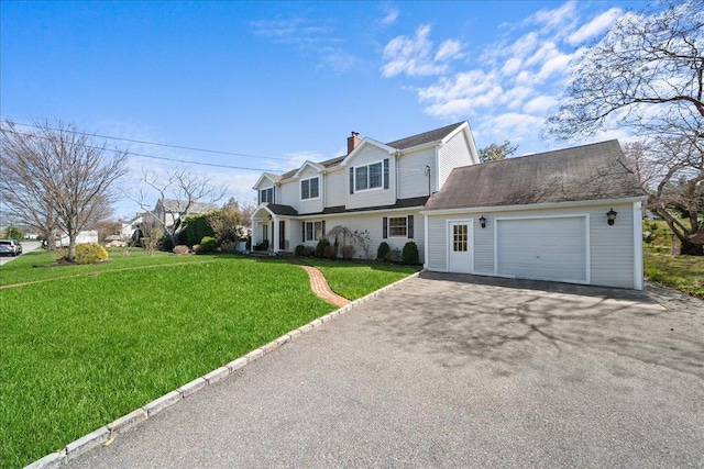 traditional-style house featuring a front lawn, driveway, a chimney, and a garage