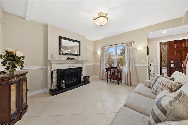 living room featuring baseboards, a fireplace with raised hearth, and light tile patterned floors