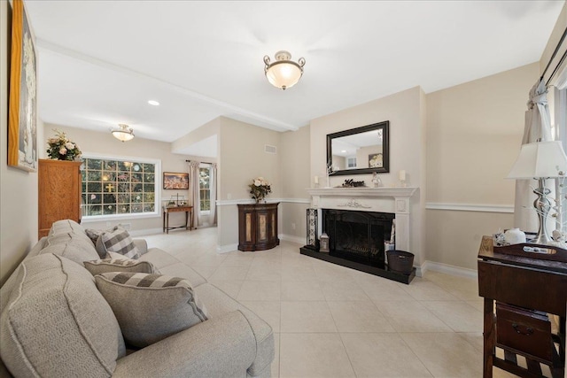living room with recessed lighting, baseboards, a fireplace with raised hearth, and light tile patterned floors
