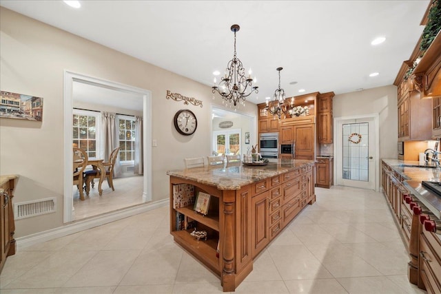 kitchen featuring a center island, open shelves, brown cabinets, an inviting chandelier, and visible vents