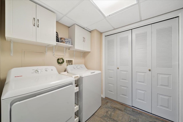 washroom with washer and dryer, cabinet space, and stone finish flooring