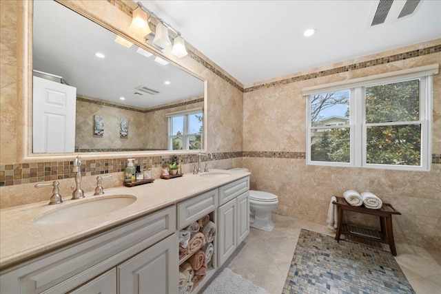 bathroom with toilet, a sink, visible vents, and double vanity