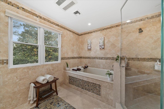 bathroom featuring a garden tub, tile walls, visible vents, and a stall shower