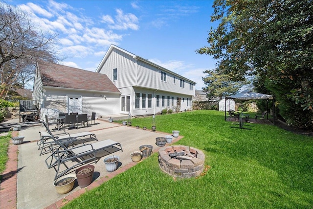 rear view of property featuring a fire pit, a yard, and a patio