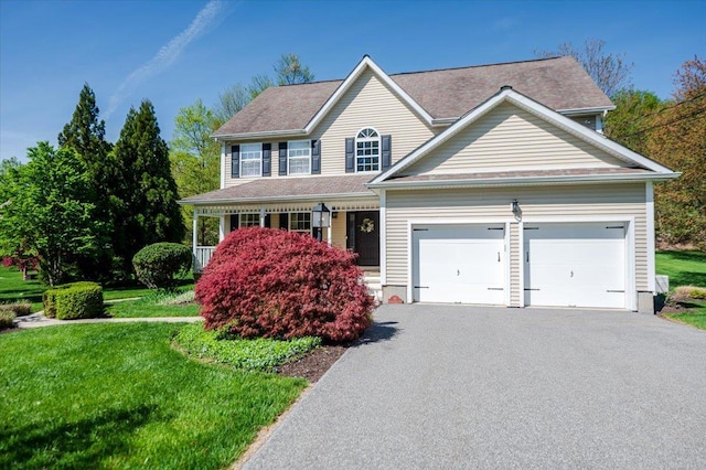 view of front of property with a garage, covered porch, driveway, and a front yard