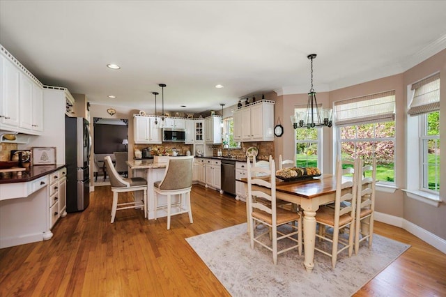 dining space with wood finished floors, baseboards, a notable chandelier, ornamental molding, and recessed lighting