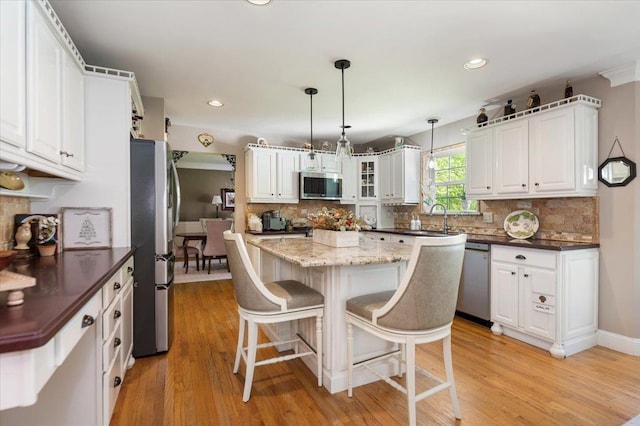 kitchen featuring tasteful backsplash, white cabinets, a breakfast bar, and stainless steel appliances