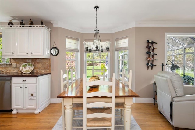 dining area with light wood-style floors, baseboards, an inviting chandelier, and crown molding